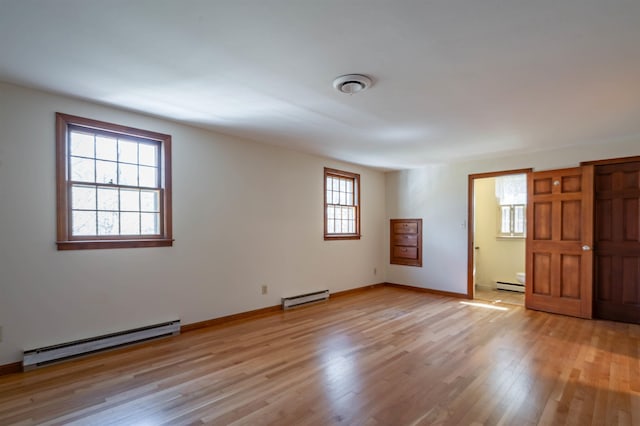 spare room with light wood-style floors, baseboards, and a baseboard heating unit