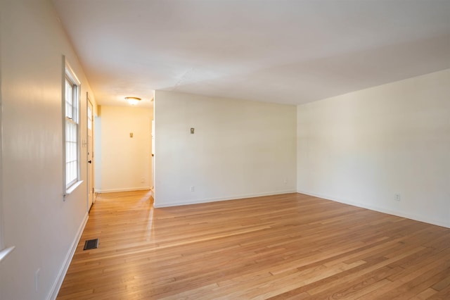 unfurnished room featuring baseboards, light wood finished floors, and visible vents