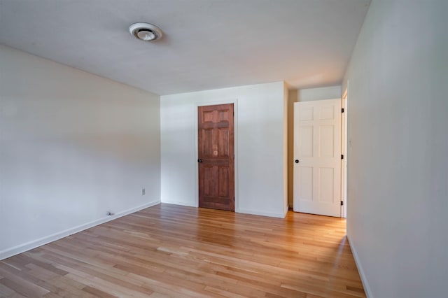 empty room featuring light wood-type flooring and baseboards