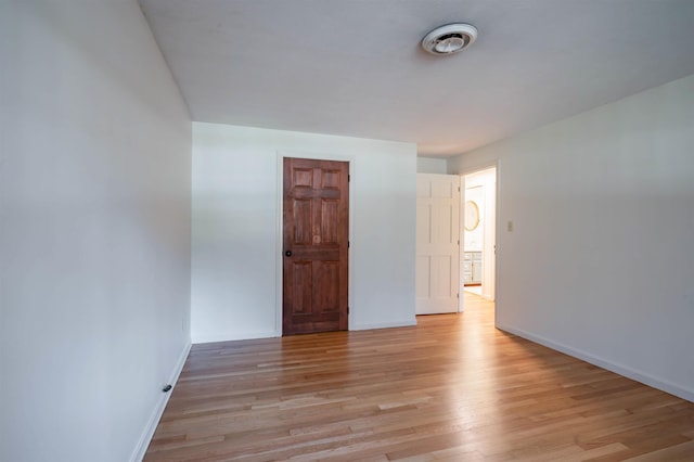 spare room with baseboards and light wood finished floors