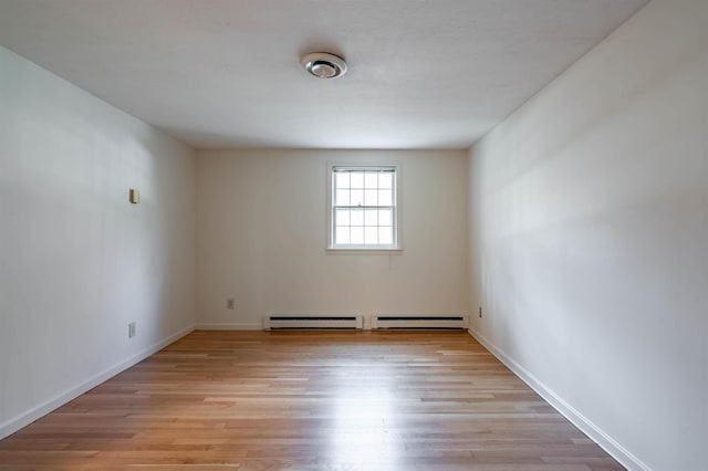 empty room featuring light wood-style floors, baseboards, and baseboard heating