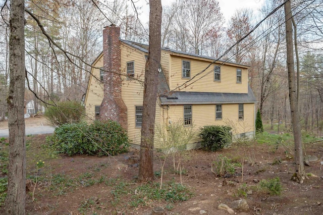 view of property exterior with a chimney and a shingled roof