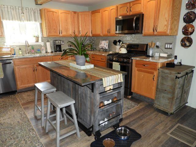 kitchen featuring stainless steel appliances, visible vents, a sink, and dark wood-type flooring