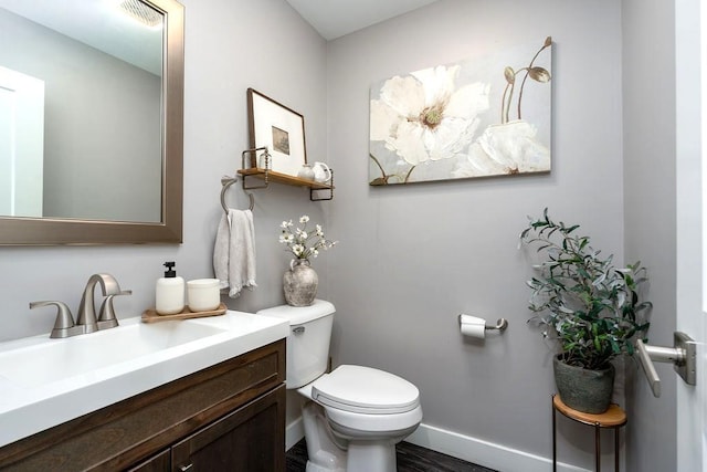 bathroom featuring toilet, baseboards, wood finished floors, and vanity