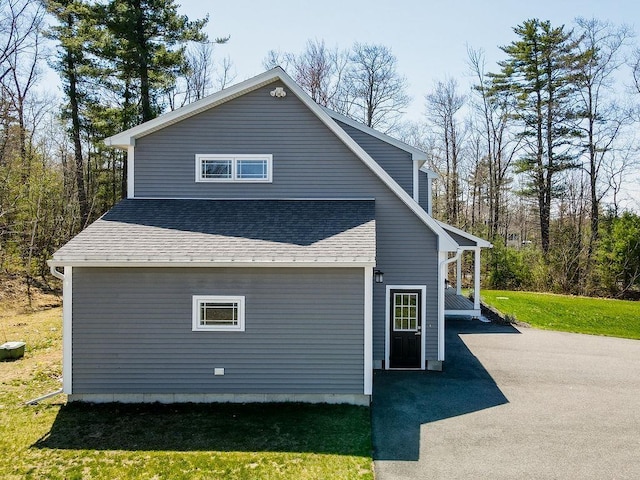 view of home's exterior featuring a yard and roof with shingles