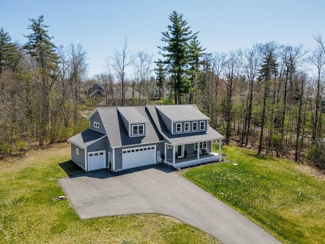 view of front of property with a porch, driveway, a front yard, and a garage