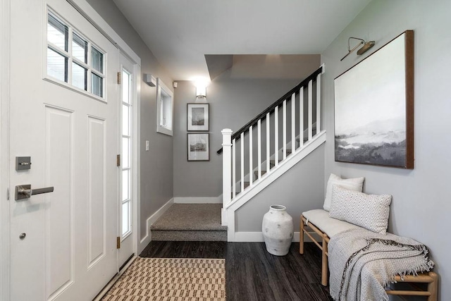 foyer featuring baseboards, wood finished floors, and stairway