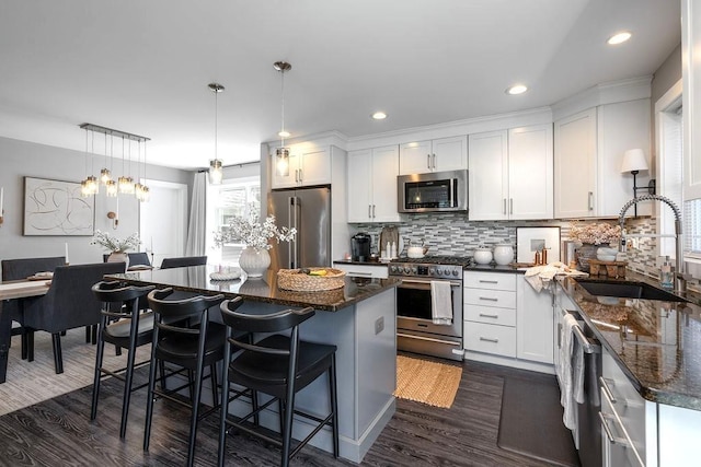 kitchen with a kitchen island, a sink, stainless steel appliances, white cabinetry, and dark wood-type flooring