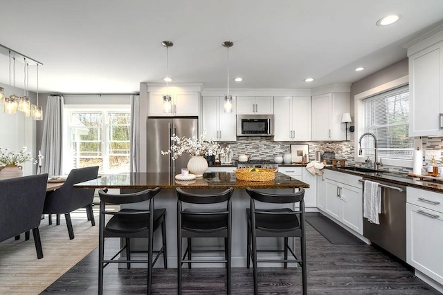 kitchen with a sink, decorative backsplash, appliances with stainless steel finishes, and a wealth of natural light
