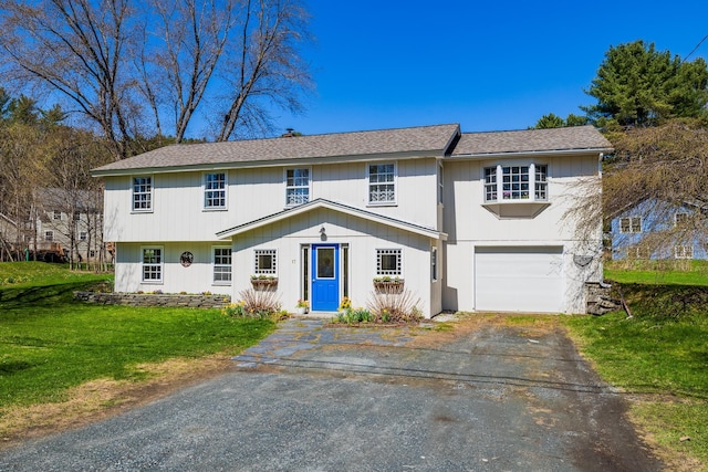 view of front of property with an attached garage, a front lawn, roof with shingles, and aphalt driveway