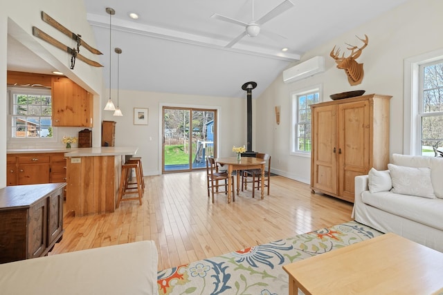 interior space featuring light wood-type flooring, a wood stove, an AC wall unit, and vaulted ceiling with beams