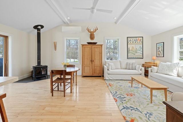 living area featuring vaulted ceiling with beams, plenty of natural light, light wood-style flooring, and a wall mounted air conditioner