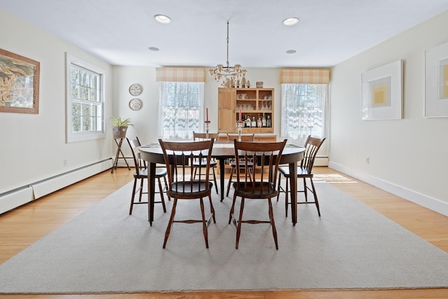 dining space with light wood-type flooring, baseboards, a chandelier, and a wealth of natural light