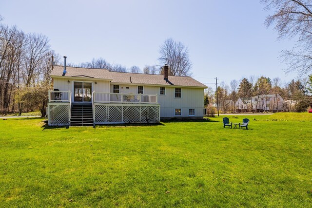 rear view of property with a chimney, a yard, and a deck
