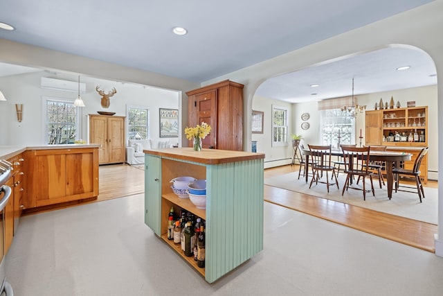 kitchen featuring open shelves, butcher block counters, recessed lighting, arched walkways, and decorative light fixtures