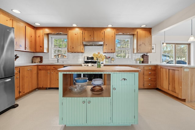 kitchen featuring freestanding refrigerator, stove, recessed lighting, under cabinet range hood, and backsplash