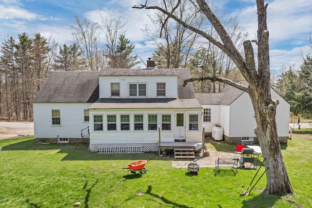 back of property with a shingled roof, a fire pit, a yard, and a chimney