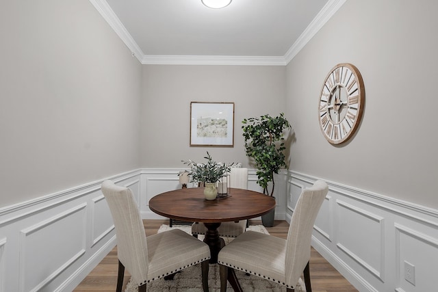 dining room featuring crown molding, a decorative wall, and light wood-type flooring