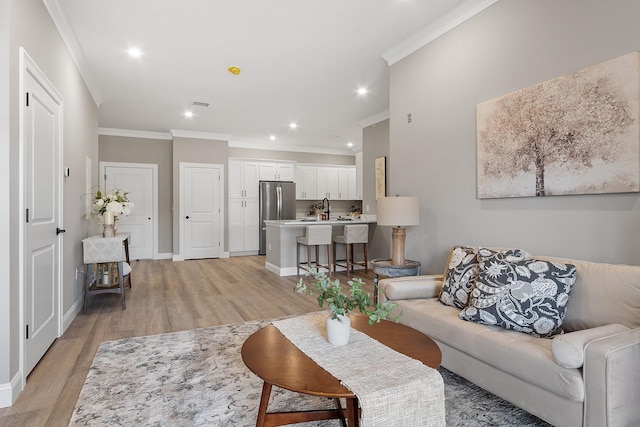 living room with light wood-style floors, ornamental molding, baseboards, and recessed lighting