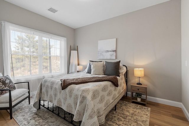 bedroom featuring baseboards, wood finished floors, and visible vents