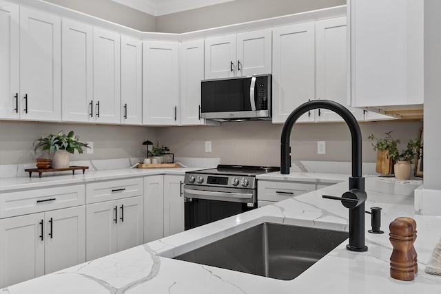 kitchen featuring white cabinets, stainless steel appliances, light stone counters, and a sink