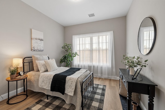 bedroom featuring baseboards, light wood finished floors, and visible vents