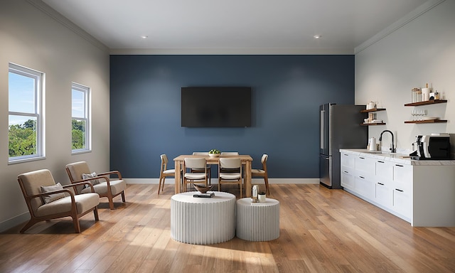 dining area featuring crown molding, light wood finished floors, baseboards, and indoor wet bar