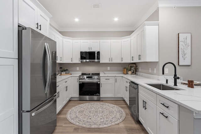 kitchen with light wood-type flooring, a sink, appliances with stainless steel finishes, and a peninsula
