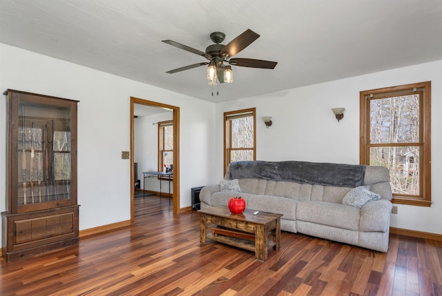 living area featuring a ceiling fan, baseboards, and wood finished floors