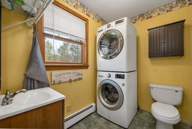bathroom featuring a sink, stacked washer and clothes dryer, a baseboard heating unit, and toilet