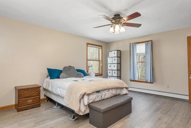bedroom featuring light wood-style floors, baseboards, a ceiling fan, and a baseboard heating unit