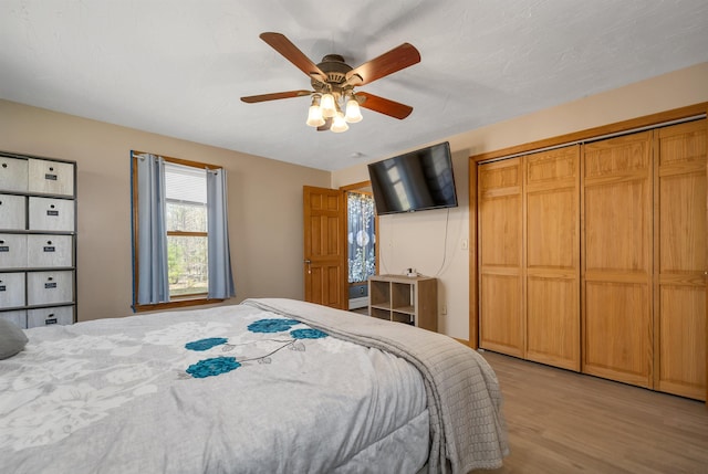 bedroom with a closet, a ceiling fan, and light wood-style floors