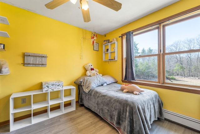 bedroom featuring a baseboard radiator, a ceiling fan, and wood finished floors