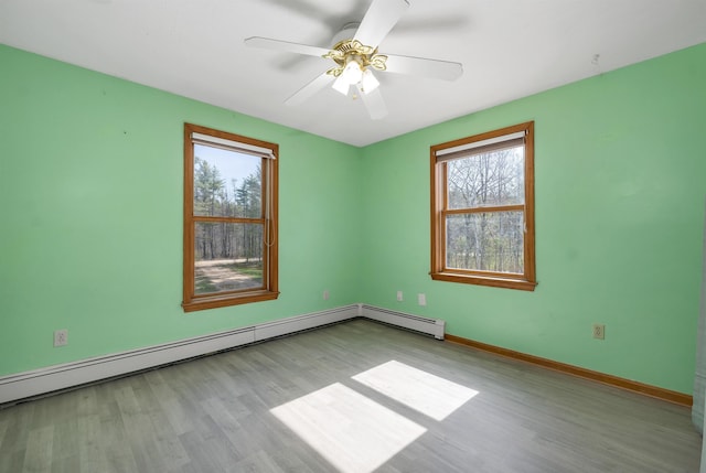 spare room featuring baseboards, wood finished floors, and a healthy amount of sunlight