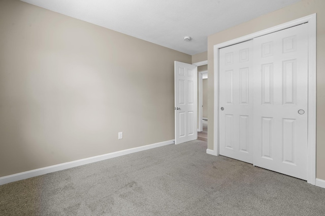 unfurnished bedroom featuring carpet floors, baseboards, and a closet