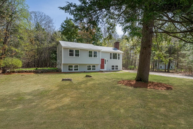 bi-level home with a chimney and a front yard