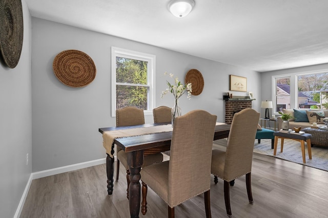 dining room featuring baseboards, wood finished floors, and a fireplace