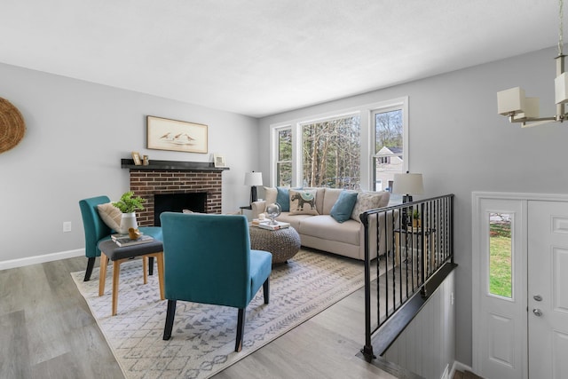 living room featuring baseboards, a brick fireplace, and wood finished floors