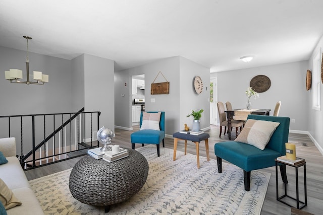 living area featuring baseboards, a chandelier, and wood finished floors