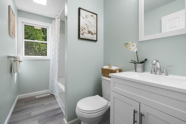 bathroom with vanity, wood finished floors, toilet, baseboards, and shower / bathtub combination with curtain