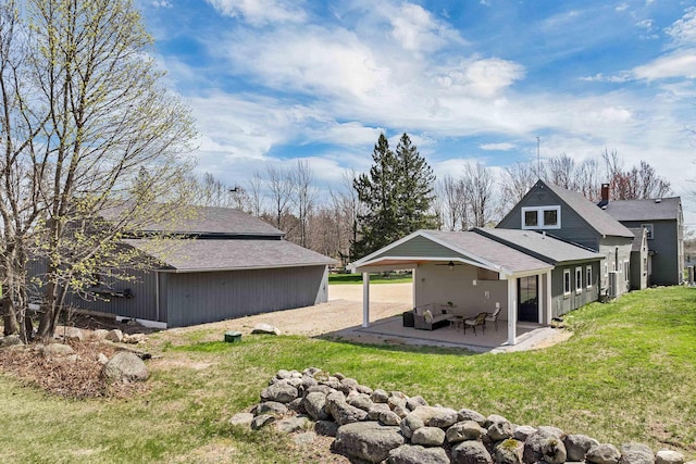 back of property featuring a ceiling fan, roof with shingles, a lawn, a patio, and an attached carport