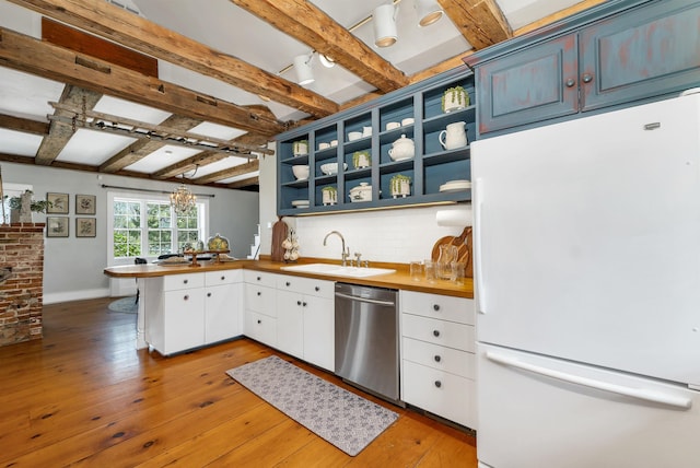 kitchen with stainless steel dishwasher, open shelves, a sink, freestanding refrigerator, and a peninsula