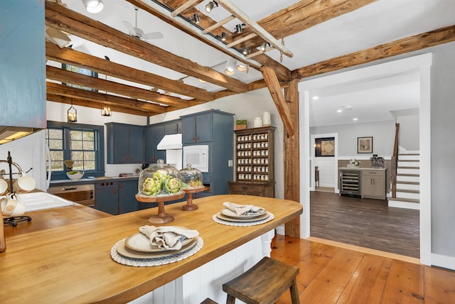 dining room with stairs, beam ceiling, wood-type flooring, wine cooler, and recessed lighting