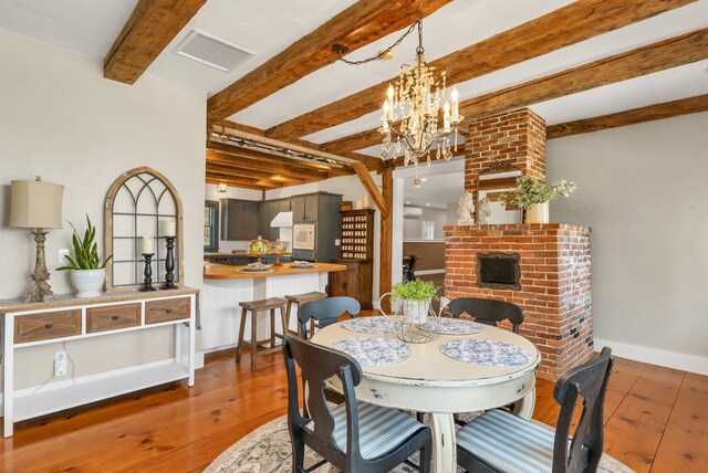 dining area with beamed ceiling, a chandelier, hardwood / wood-style floors, and visible vents