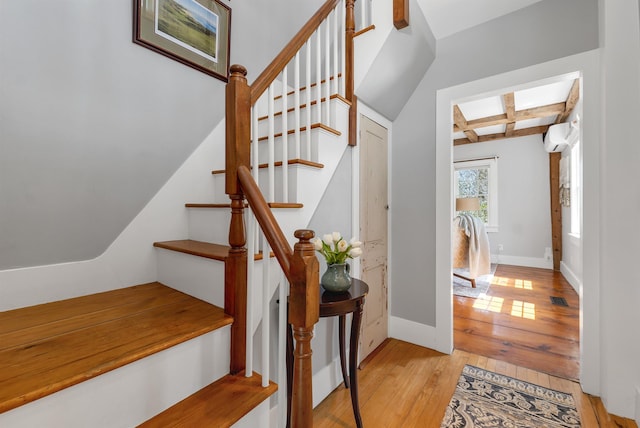 stairs with a wall unit AC, baseboards, beamed ceiling, coffered ceiling, and hardwood / wood-style floors