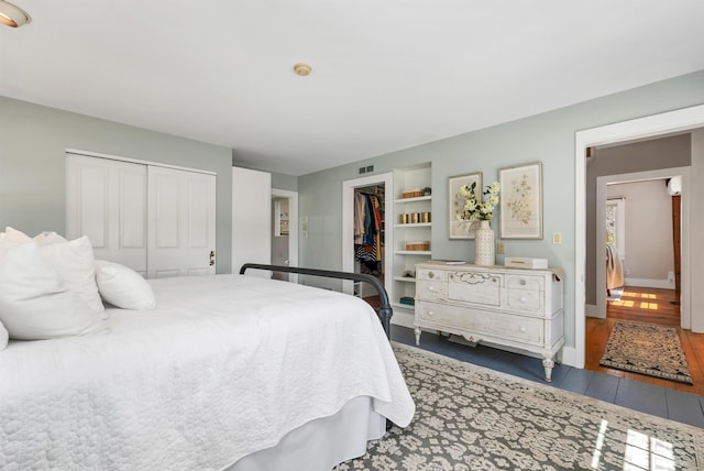 bedroom with baseboards, a closet, wood finished floors, and visible vents