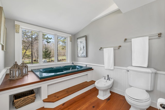 full bathroom with wainscoting, toilet, wood finished floors, a bidet, and a bath