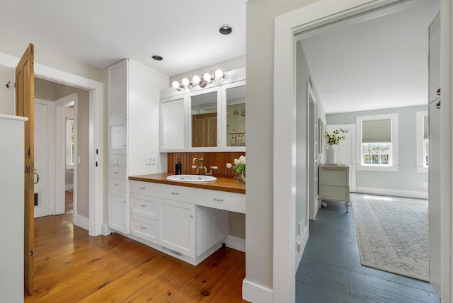 bathroom with wood-type flooring, baseboards, visible vents, and vanity