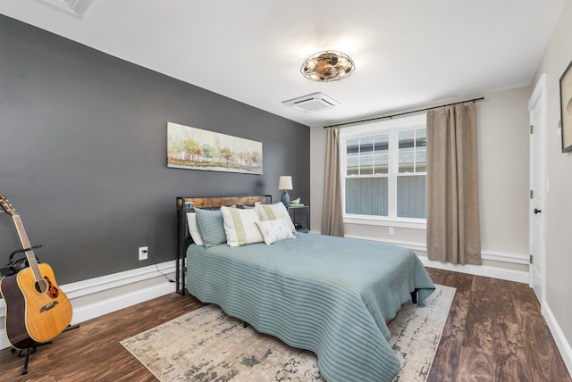 bedroom with visible vents, baseboards, and wood finished floors