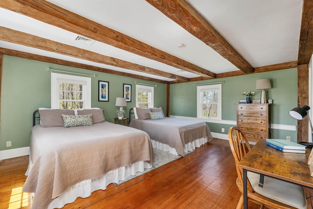 bedroom with visible vents, wood-type flooring, baseboards, and beamed ceiling